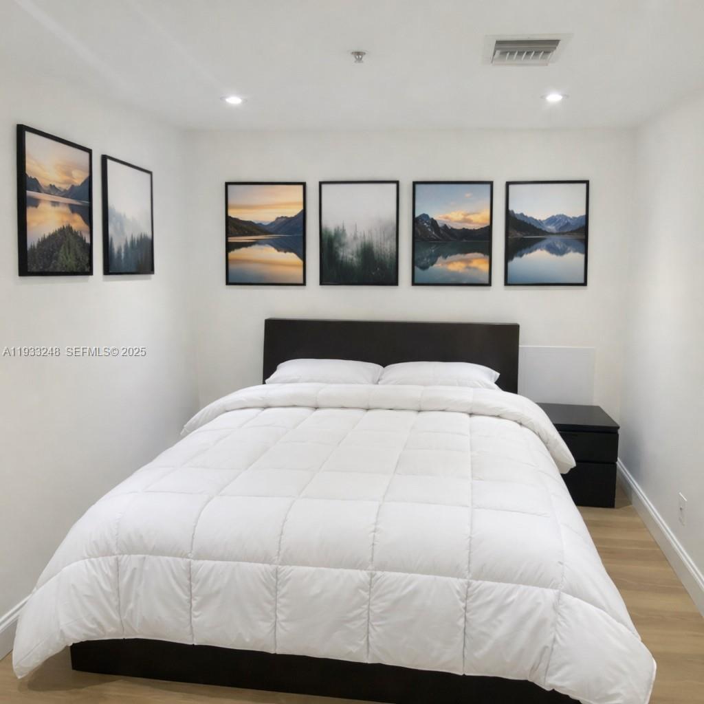 9499 Collins Avenue, Unit 903 Surfside, FL 33154 - Photo 7 of 14 a bedroom with a large bed and painting on the wall