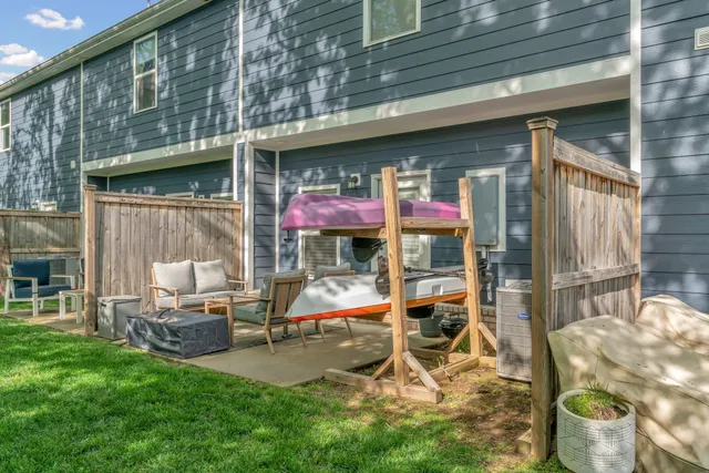a house that has a big yard and couches chairs with wooden fence