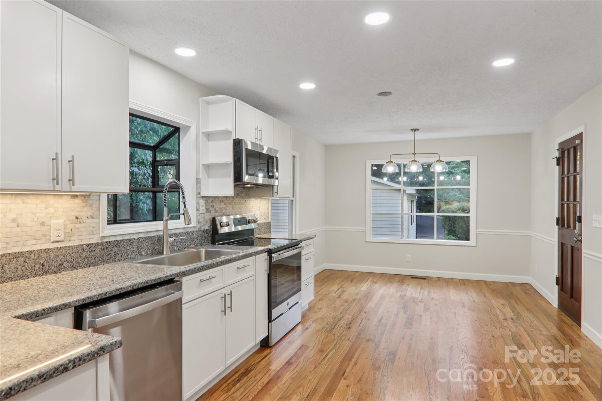5 Timothy Lane Candler, NC 28715 - Photo 16 of 48 a kitchen with stainless steel appliances granite countertop a sink stove and wooden floor