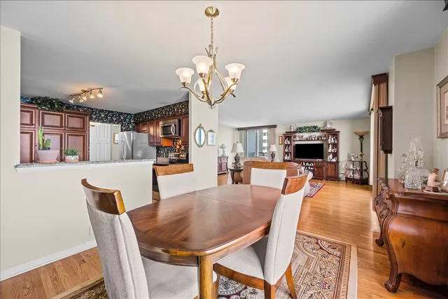 a dining room with wooden floor a chandelier a wooden table and chairs