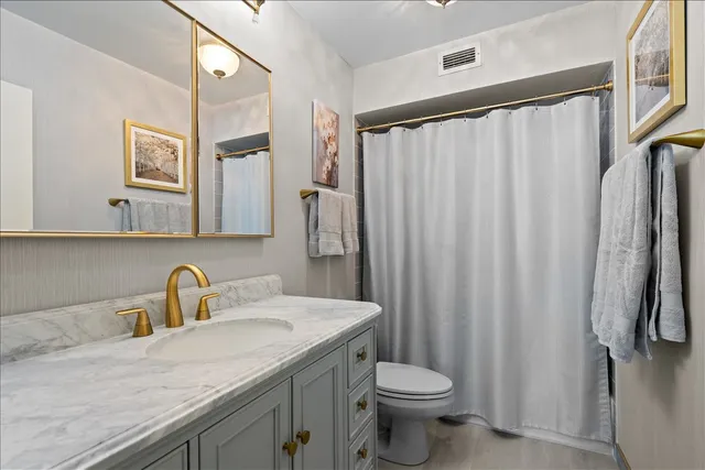 a bathroom with a granite countertop sink toilet and a mirror