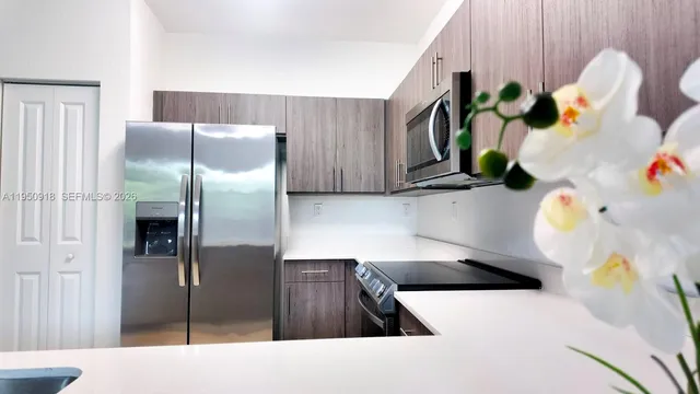 a kitchen with stainless steel appliances kitchen island granite countertop a refrigerator a stove and a sink