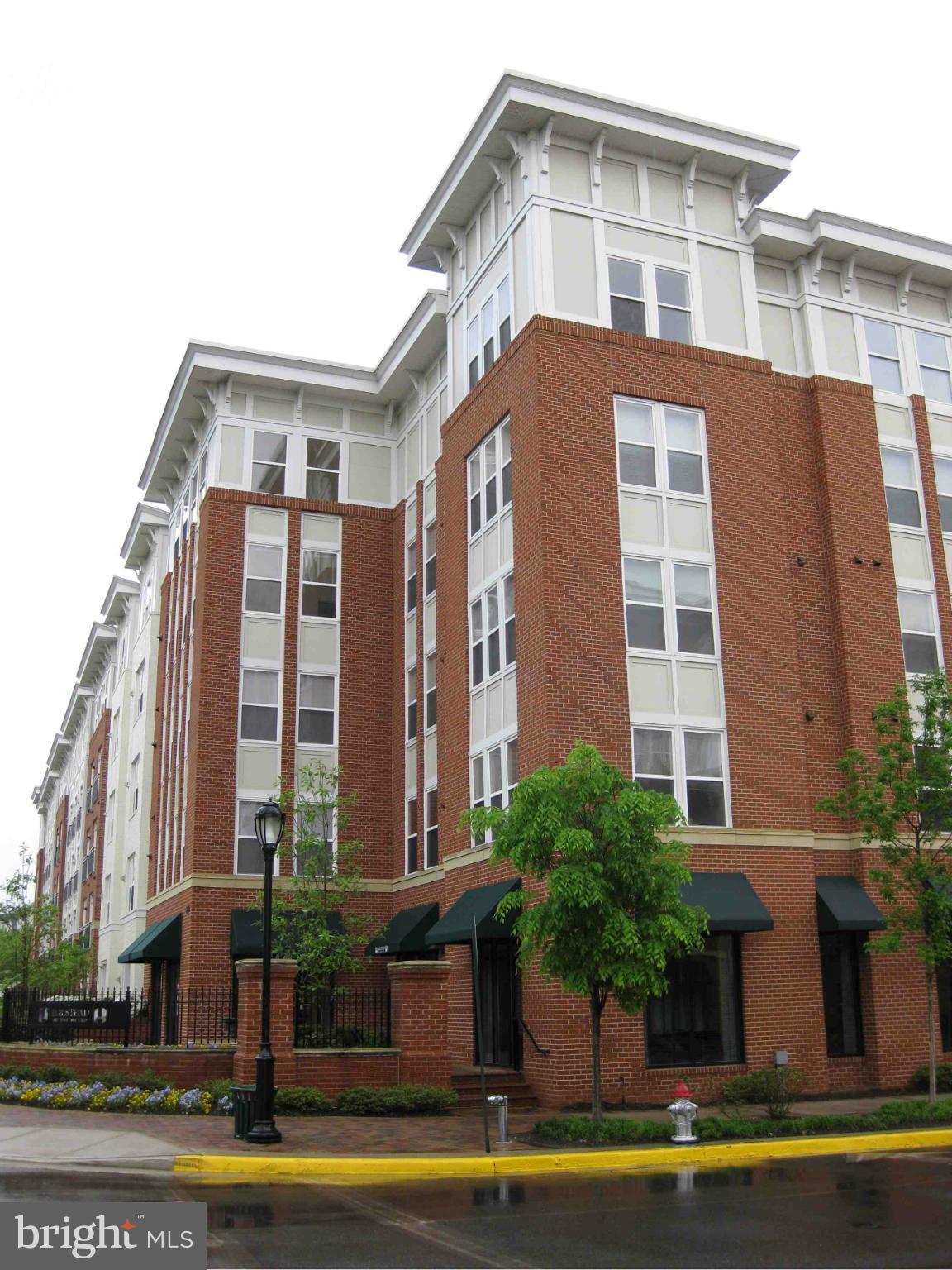 a front view of multi story residential apartment building with yard and seating space