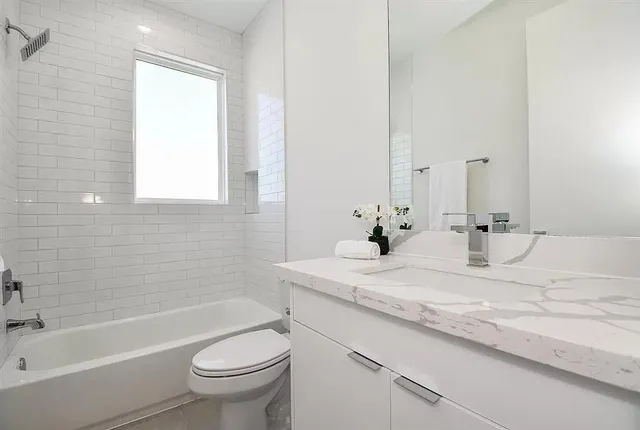 a bathroom with a granite countertop sink toilet mirror and bathtub