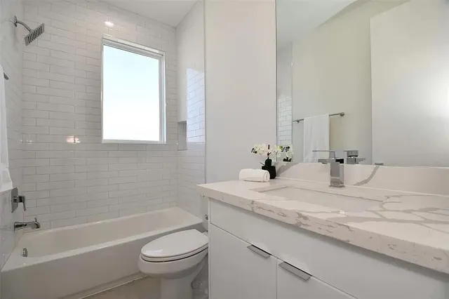 a bathroom with a granite countertop sink a toilet and shower