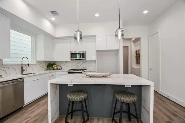 a kitchen with kitchen island granite countertop a sink and refrigerator