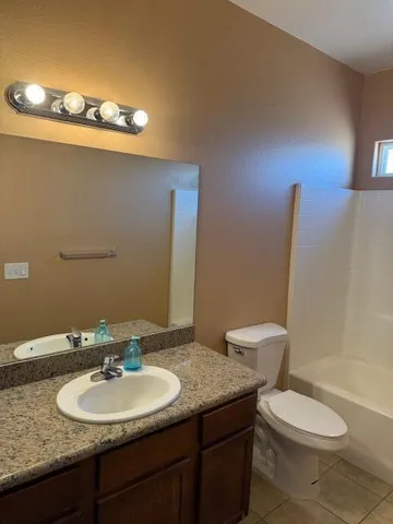 a bathroom with a granite countertop toilet a sink and a mirror