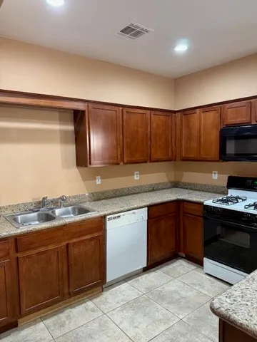a kitchen with stainless steel appliances granite countertop wooden cabinets a stove top oven a sink and dishwasher