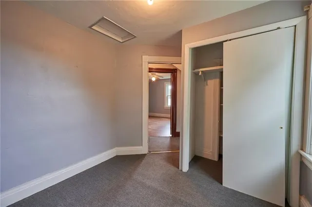 a view of an empty room with closet and a window