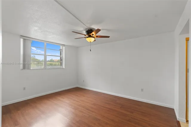 a view of an empty room with window and wooden floor