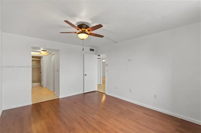 a view of a room with wooden floor and ceiling fan