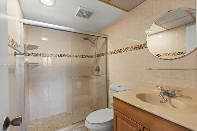 a bathroom with a sink a mirror a toilet and shower
