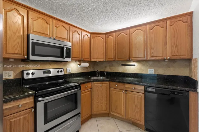 a kitchen with stainless steel appliances granite countertop a stove microwave and cabinets