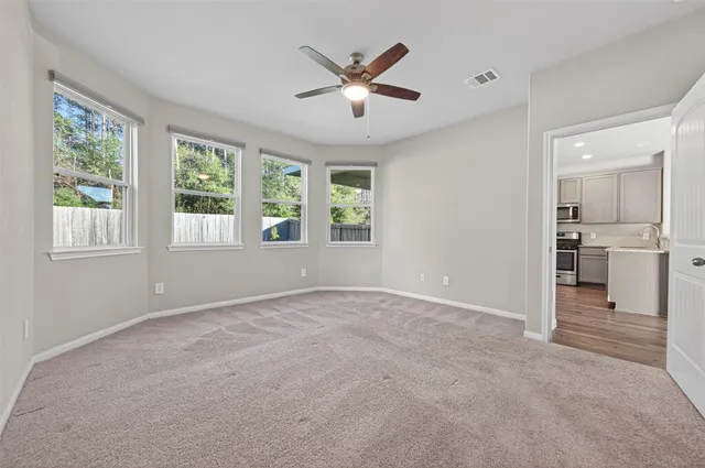 a view of an empty room with a window and a kitchen