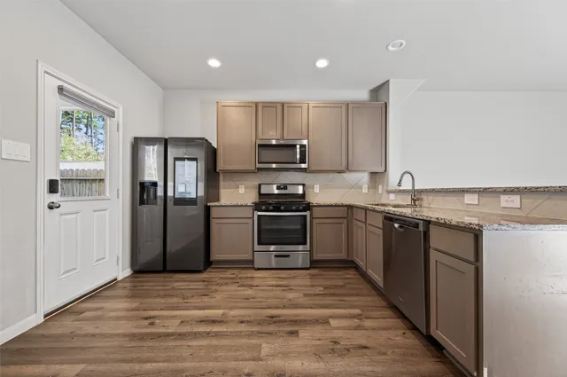a kitchen with granite countertop a refrigerator and a stove top oven