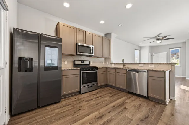 a kitchen with kitchen island granite countertop a refrigerator and a sink