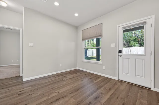 a view of an empty room with wooden floor and a window