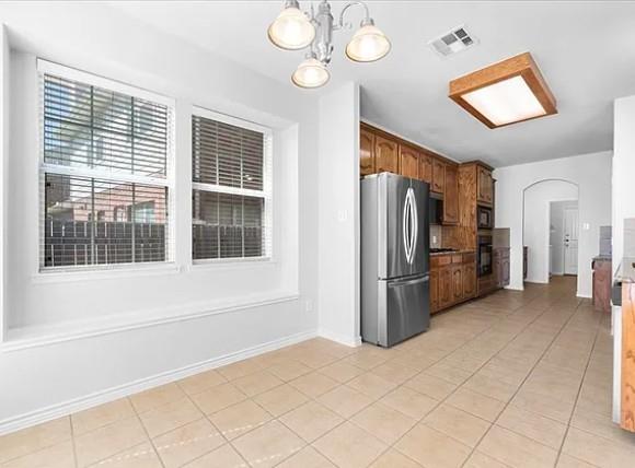 8401 Hitching Trail McKinney, TX 75070 - Photo 20 of 39 Kitchen featuring arched walkways, freestanding refrigerator, light tile patterned flooring, hanging light fixtures, and wood finish cabinets