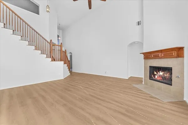 a view of an empty room with wooden floor fireplace and a window
