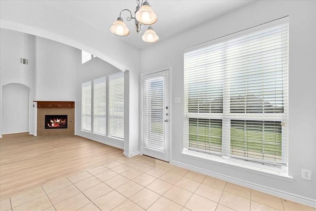 8401 Hitching Trail McKinney, TX 75070 - Photo 24 of 39 Unfurnished living room featuring light tile patterned flooring, a tile fireplace, and a chandelier