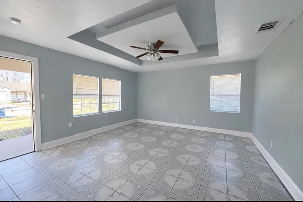 an empty room with windows and fan
