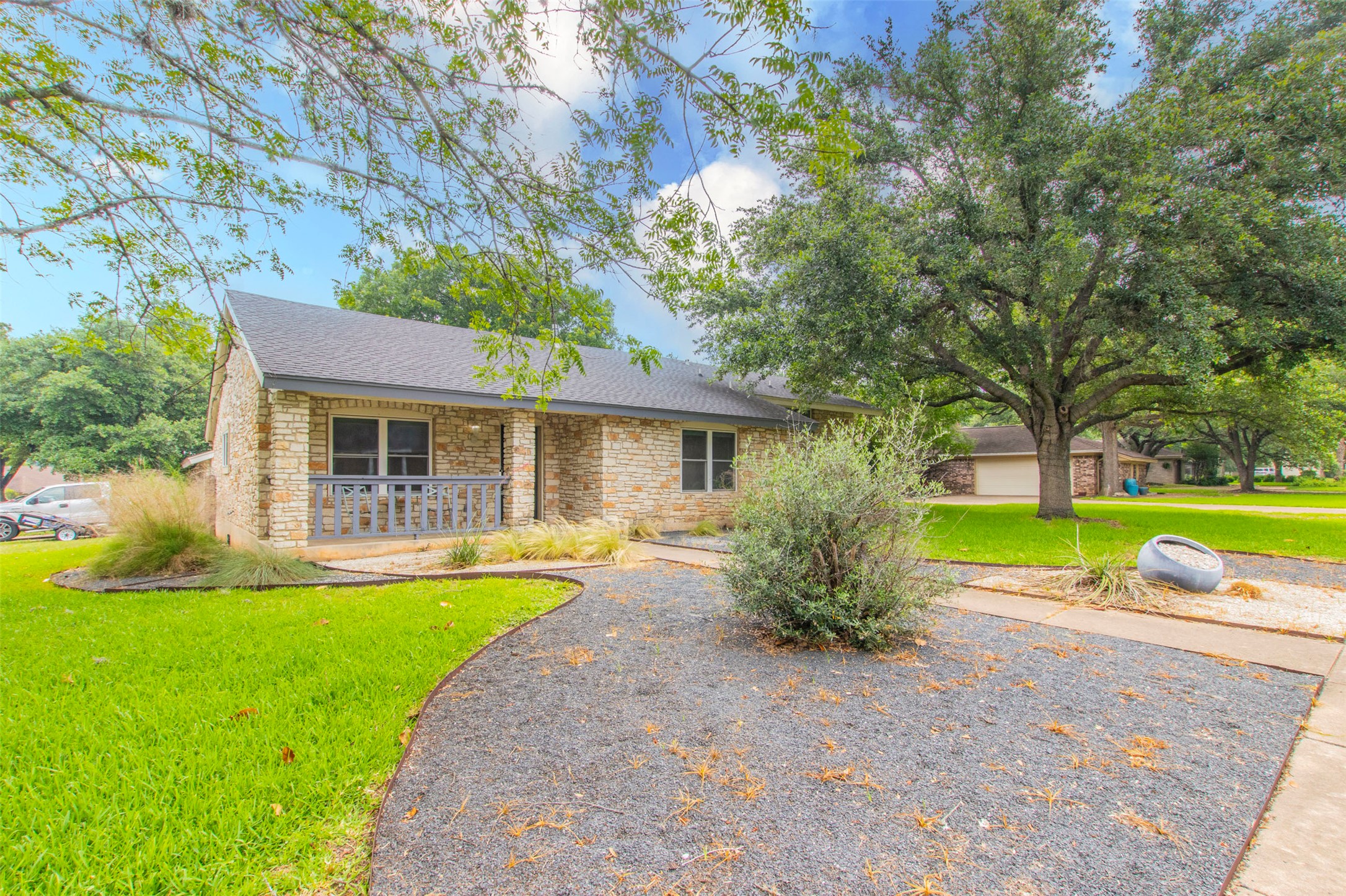 Single story home featuring a front yard, stone siding, roof with shingles, and covered porch
