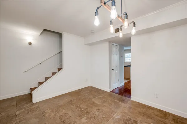 a view of empty room with wooden floor and kitchen view