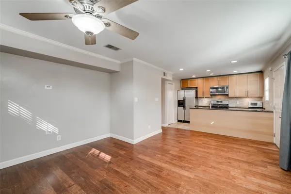 a view of kitchen with kitchen island wooden floor center island and stainless steel appliances