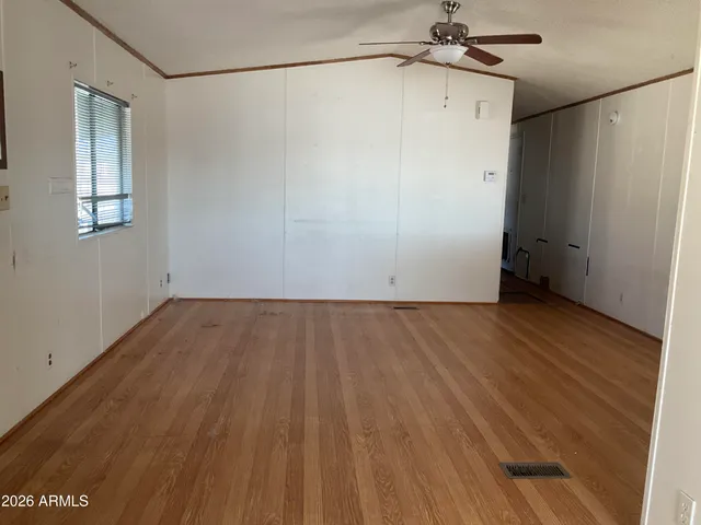 an empty room with wooden floor and fan