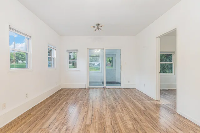 a view of an empty room with wooden floor and a window