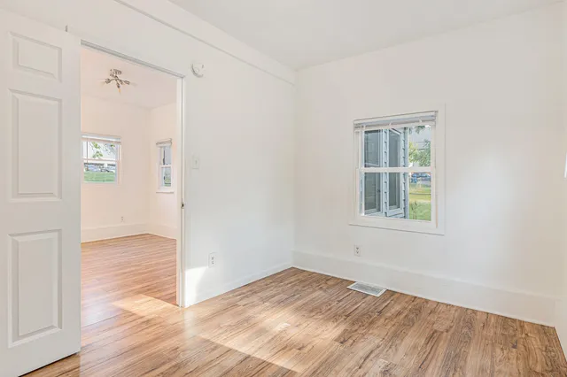 an empty room with wooden floor and windows
