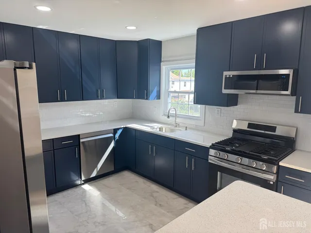 a kitchen with kitchen island granite countertop stainless steel appliances wooden cabinets a sink and a stove