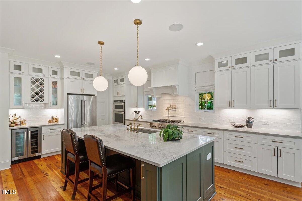 2613 Bedford Avenue Raleigh, NC 27607 - Photo 10 of 44 a kitchen with stainless steel appliances kitchen island granite countertop a table chairs and wooden cabinets