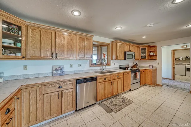 a open kitchen with granite countertop a sink dishwasher stove top oven and cabinets
