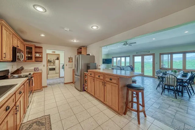 a kitchen with stainless steel appliances kitchen island granite countertop a stove a sink a refrigerator cabinets and dining table