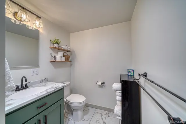 a bathroom with a granite countertop sink a toilet and a mirror