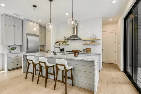 a kitchen with cabinets a sink dishwasher a stove and a dining table with wooden floor