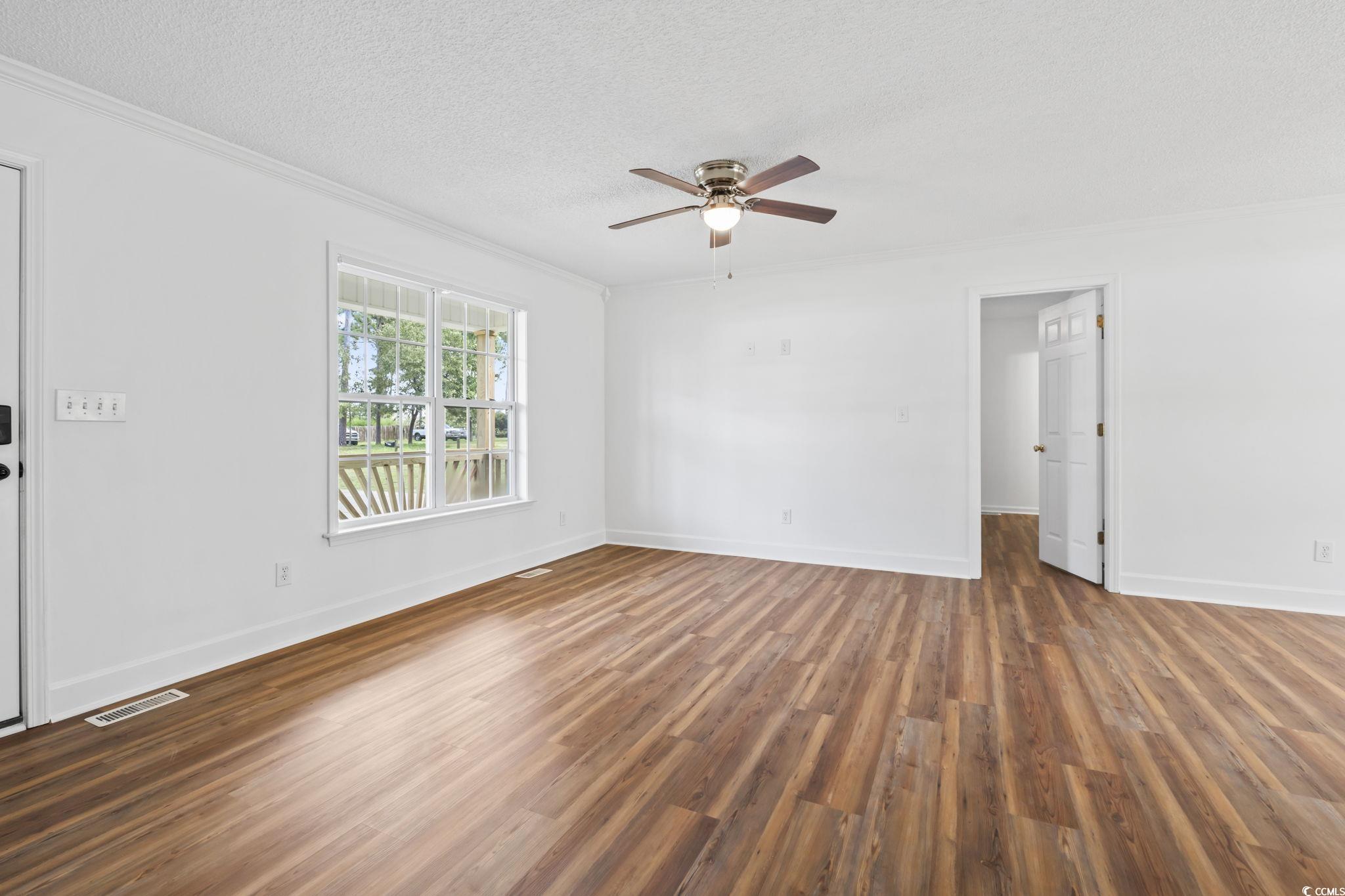 568 Rosedale Drive Aynor, SC 29511 - Photo 6 of 38 Unfurnished room featuring a textured ceiling, ornamental molding, dark wood-style flooring, and a ceiling fan
