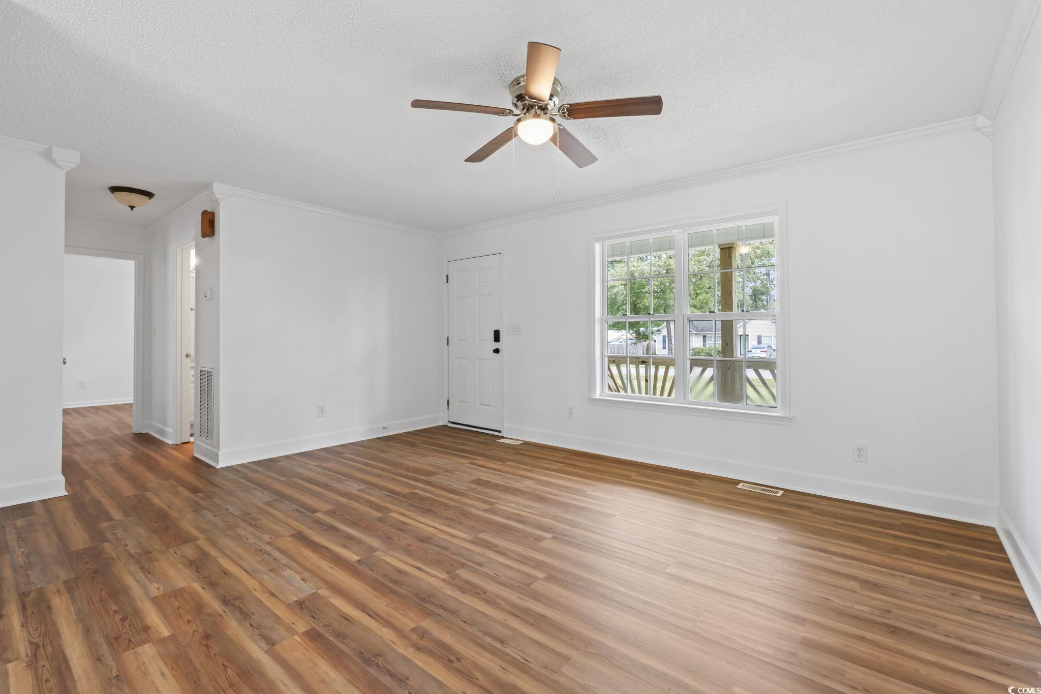 568 Rosedale Drive Aynor, SC 29511 - Photo 7 of 38 Unfurnished living room with crown molding, wood finished floors, a textured ceiling, and ceiling fan