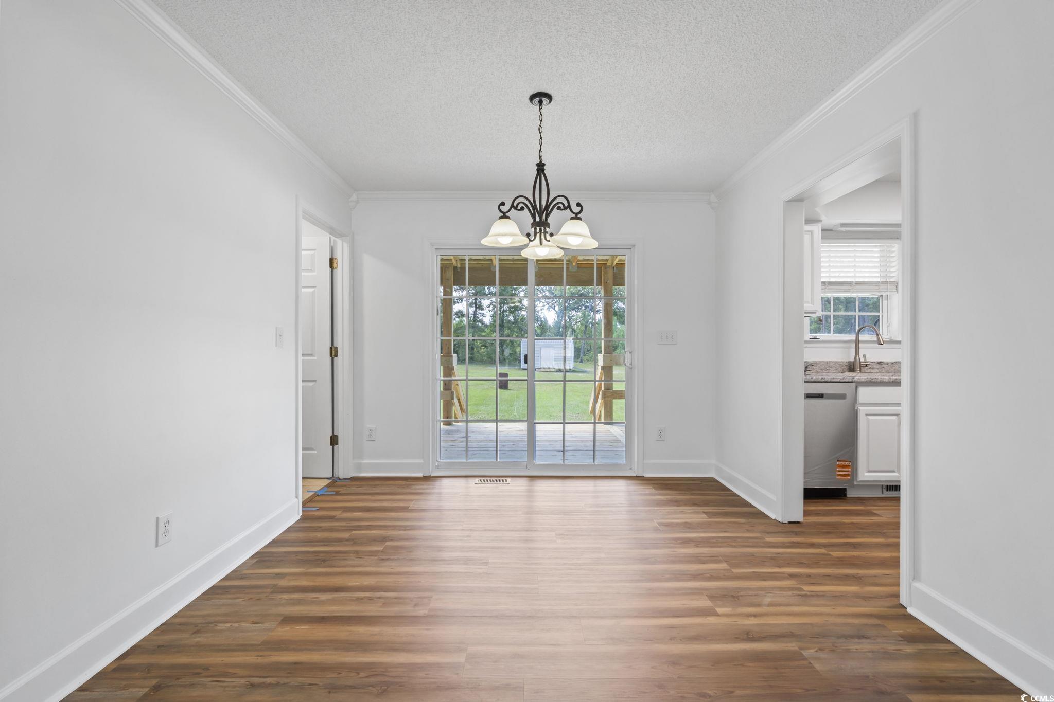 568 Rosedale Drive Aynor, SC 29511 - Photo 9 of 38 Unfurnished dining area featuring ornamental molding, a textured ceiling, a chandelier, and dark wood-type flooring