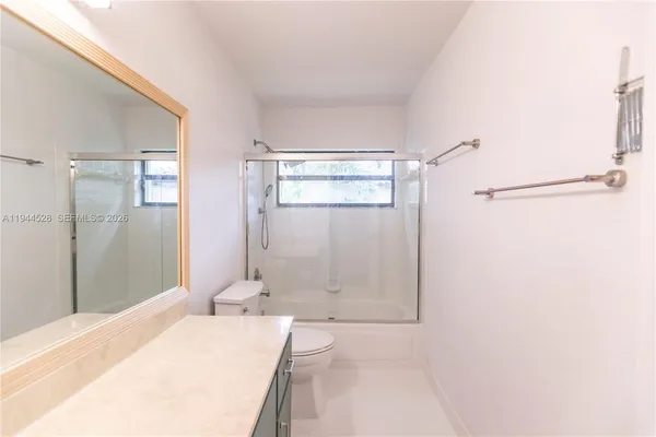 a bathroom with a granite countertop sink a toilet and shower
