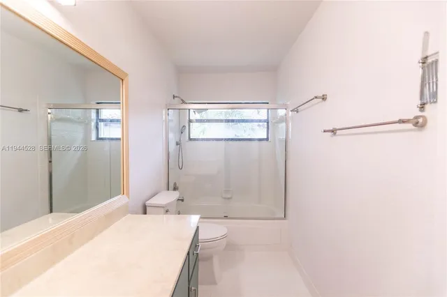 a bathroom with a granite countertop sink a toilet and shower