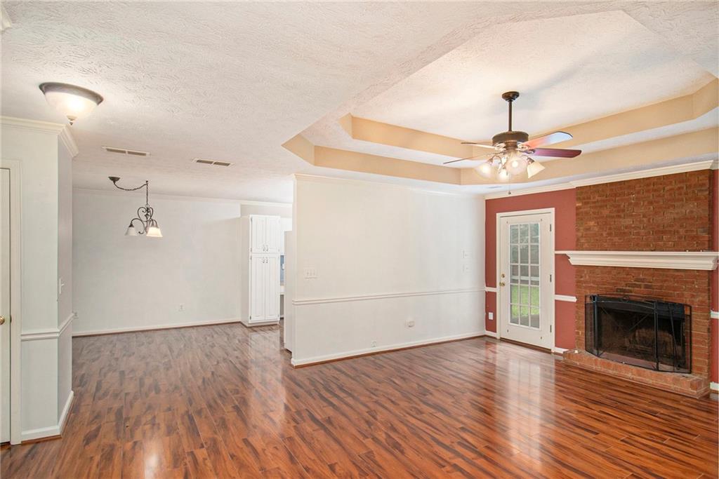340 Radcliff Trace Covington, GA 30016 - Photo 8 of 38 an empty room with wooden floor a ceiling fan a fireplace and windows