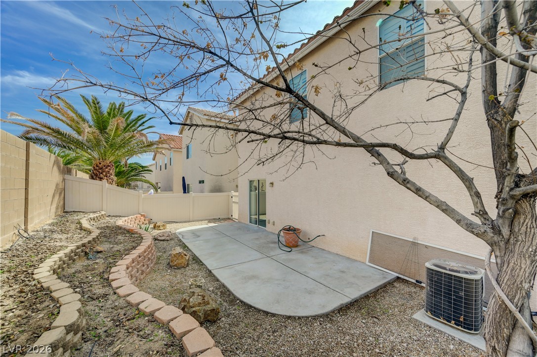8918 Houston Ridge Avenue Las Vegas, NV 89178 - Photo 35 of 35 A spacious backyard with mature trees, a concrete patio, and garden beds awaits personalization.