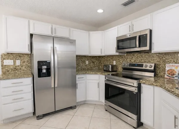 a kitchen with stainless steel appliances granite countertop a refrigerator stove and microwave