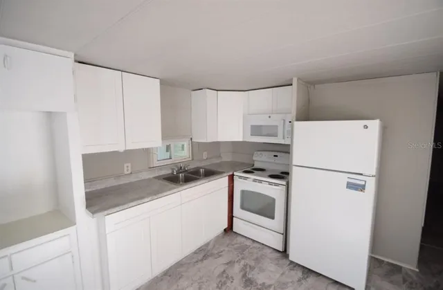 a kitchen with a sink a stove a refrigerator and white cabinets