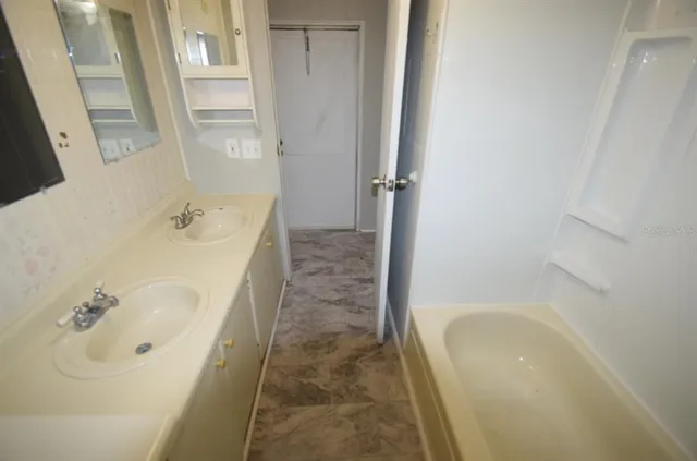 a bathroom with a tub a sink and a large mirror