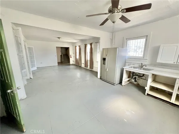 a view of a livingroom with a fireplace a ceiling fan and wooden floor