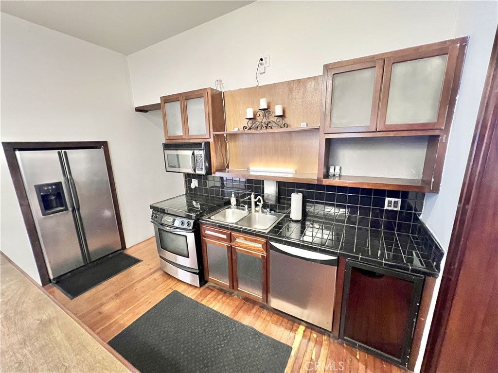 606 East 6th Street Los Angeles, CA 90021 - Photo 7 of 20 a kitchen with stainless steel appliances granite countertop a refrigerator a sink dishwasher a stove and white countertops with cabinets