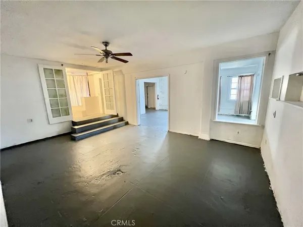 an empty room with windows and ceiling fan